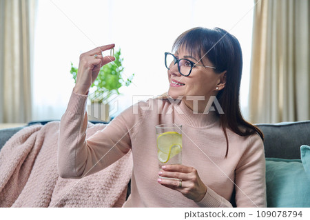 Middle-aged woman taking dietary supplement, fish oil capsule, omega 3 109078794