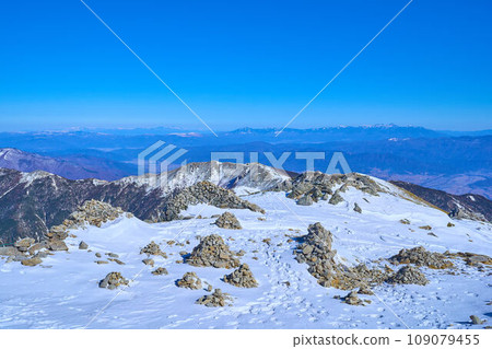 View of the northeast side (Shogogashiyama, Yatsugatake, etc.) and cairns from the summit of Mt. Kisokomagatake in Kamiina District, Nagano Prefecture in winter 109079455