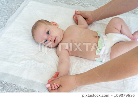 Mother's hands do gymnastics with the baby. Arms spread to the sides 109079656