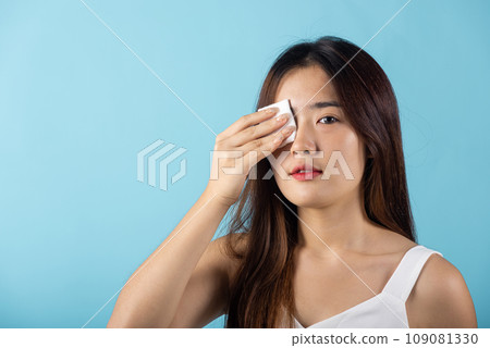 Facial Beauty Treatment Hygiene skin. Asian beautiful young woman removing cosmetic make up using pad cotton face cleaner disc, studio shot isolated on blue background, Happy female cleaning eyes Facial Beauty Treatment Hygiene skin. Asian beautiful young woman removing cosmetic make up using pad cotton face cleaner disc, studio shot isolated on blue background, Happy female cleaning eyes 109081330