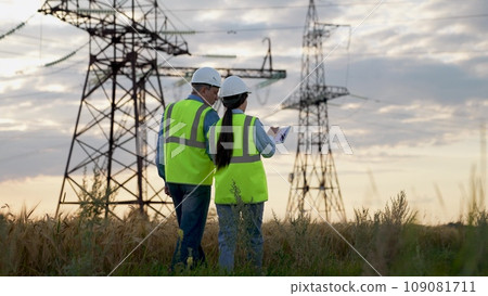 Engineer gives instructions to trainee with tablet at electric power substation Engineer gives instructions to trainee with tablet at electric power substation 109081711