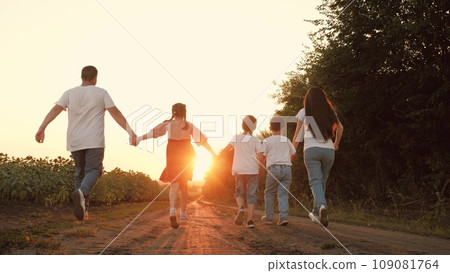 Sportive family with little children run joining hands along road at sunset Sportive family with little children run joining hands along road at sunset 109081764