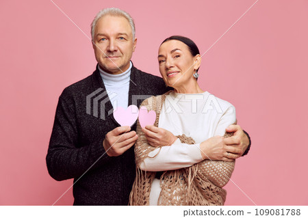 Portrait of attractive, beautiful married couple, senior man and woman hugging, celebrating anniversary against pink studio background. Valentine's Day 109081788