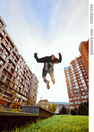 Fish eye effect photo of young man, guy performing insane jumps and breathtaking salto in air in action. Extreme sport activity, free running. Fish eye effect photo of young man, guy performing insane jumps and breathtaking salto in air in action. Extreme sport activity, free running. 109081956