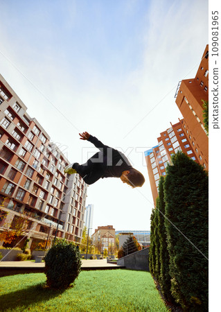 Fish eye effect photo of young man, guy performing insane tricks and breathtaking flips in air in motion. Extreme sport activity, free running. Fish eye effect photo of young man, guy performing insane tricks and breathtaking flips in air in motion. Extreme sport activity, free running. 109081965