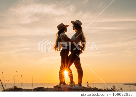 Mother daughter sunset. Mother and daughter stand on the beach, hugging and looking at each other enjoying the sunset. Mother daughter sunset. Mother and daughter stand on the beach, hugging and looking at each other enjoying the sunset. 109082833