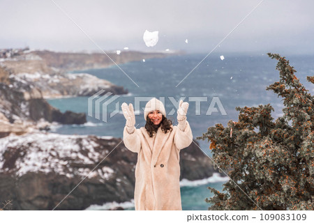 Woman snow sea. Amidst a wintry backdrop, a woman in a beige faux fur coat gleefully engages in a snowball fight, adding joy to the serene seascape. Woman snow sea. Amidst a wintry backdrop, a woman in a beige faux fur coat gleefully engages in a snowball fight, adding joy to the serene seascape. 109083109