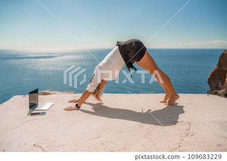 Freelance women sea working on the computer. Good looking middle aged woman typing on a laptop keyboard outdoors with a beautiful sea view. The concept of remote work. 109083229