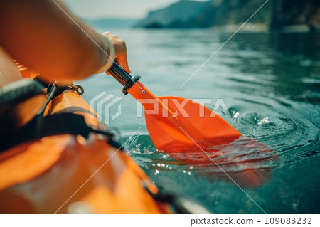 Kayak paddle sea vacation. Person paddles with orange paddle oar on kayak in sea. Leisure active lifestyle recreation activity rest tourism travel Kayak paddle sea vacation. Person paddles with orange paddle oar on kayak in sea. Leisure active lifestyle recreation activity rest tourism travel 109083232