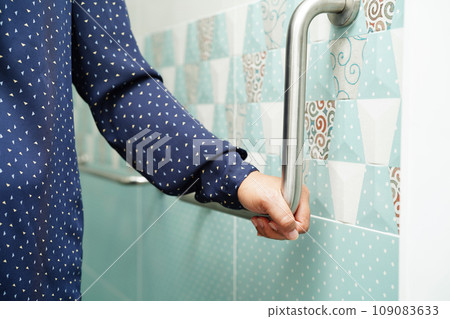 Asian woman patient use toilet support rail in bathroom, handrail safety grab bar, security in nursing hospital. 109083633