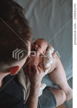 portrait of a young dad hugging and kissing his newborn baby while lying on the bed in the bedroom portrait of a young dad hugging and kissing his newborn baby while lying on the bed in the bedroom 109085243