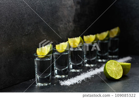 Tequila with lime and sea salt on a black table. 109085322