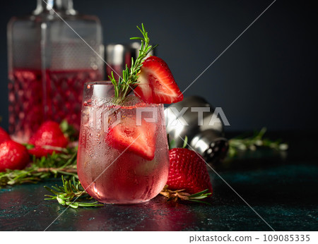 Cocktail with ice, strawberries, and rosemary. 109085335