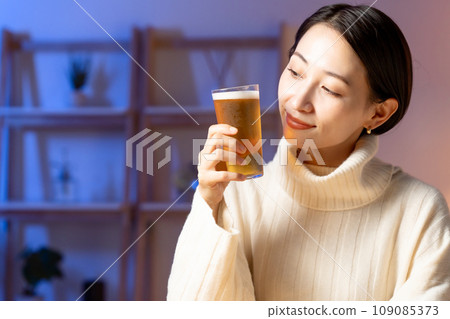 Woman drinking beer at home 109085373