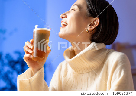 Woman drinking beer at home Woman drinking beer at home 109085374