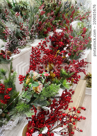 Christmas artificial berries for decoration prepared for sale in supermarket. Variety of colorful decoration on wooden shelves of large shop. 109085676