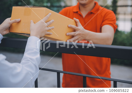 Asian Woman Receiving Product from delivery man at Home, Young Owner Woman Order Product from Smartphone Application, Woman with Online Business or SME Concept. Asian Woman Receiving Product from delivery man at Home, Young Owner Woman Order Product from Smartphone Application, Woman with Online Business or SME Concept. 109085822