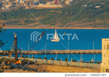 Very expensive land near the coast of the ocean, in which construction work is being carried out. In the background, you can see a blurred yacht, like a view from a future luxury property Very expensive land near the coast of the ocean, in which construction work is being carried out. In the background, you can see a blurred yacht, like a view from a future luxury property 109087265