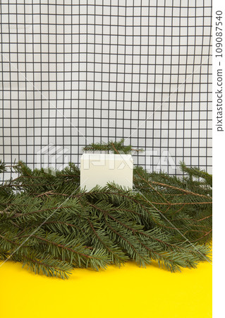 cube among fir branches on a grid background 109087540