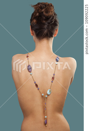 Elegant brunette female model with sautoir necklace on her back on blue background Elegant brunette female model with sautoir necklace on her back on blue background 109092225