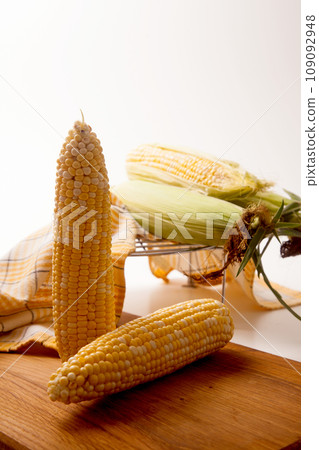 Cutting board with two cobs sweet corn on white wooden background.. Cutting board with two cobs sweet corn on white wooden background.. 109092948