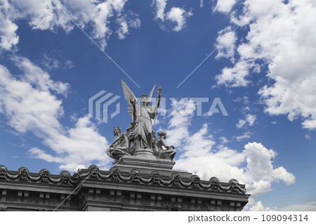 Golden statue of Liberty on the roof of the Opera Garnier (Garnier Palace)  against the sky with clouds. Sculpted by Charles Gumery in 1869. Paris, France. UNESCO World Heritage Site 109094314