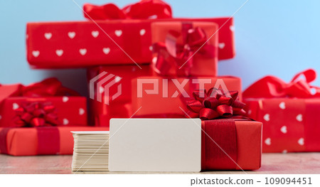 Stack of white paper business cards and gifts wrapped in red paper on a blue background 109094451
