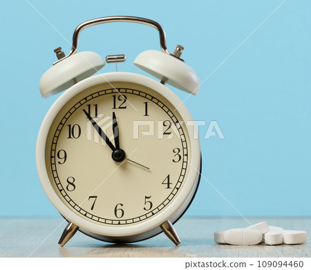 Round alarm clock and white oval tablets Round alarm clock and white oval tablets 109094460