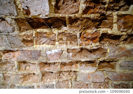 Close-up outdoor view of part of an ancient stone wall with a textured surface. An abstract image of a brown cemented, durable facade. Close-up outdoor view of part of an ancient stone wall with a textured surface. An abstract image of a brown cemented, durable facade. 109096080