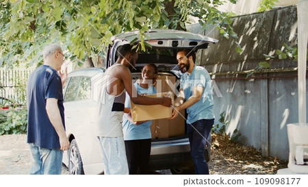 Hunger relief team, comprising of African Americans and Caucasians, distribute donated food to the homeless and others in need. Charity workers providing humanitarian aid to the less privileged. 109098177