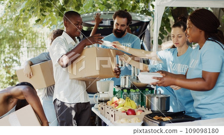 Group of volunteers handing out packed food to needy such as the elderly and homeless people. The sincere gesture of kindness makes the less fortunate individuals happy and relieves their suffering. 109098180