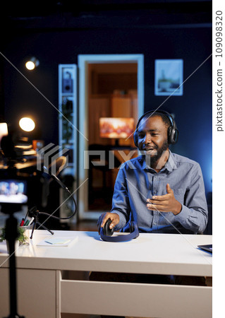 Media star excited to review newly launched gaming headphones, comparing features with older models. Technology internet show host filming video online channel, analyzing listening device 109098320