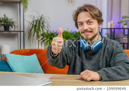 Happy Caucasian young man looking approvingly at camera show thumbs up like positive sign good news Happy Caucasian young man looking approvingly at camera show thumbs up like positive sign good news 109099646