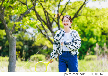 微笑的年輕女子在戶外享受羽毛球 109101625