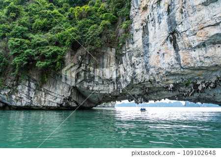 越南:一個人在奇岩怪石環繞的下龍灣劃著獨木舟,到達一個旅遊景點。 越南:一個人在奇岩怪石環繞的下龍灣劃著獨木舟,到達一個旅遊景點。 109102648