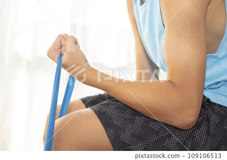 Teenage man training his arms with a training tube Teenage man training his arms with a training tube 109106513