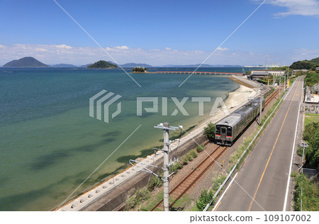香川縣三豐市美濃町海上漂浮的兒童守護神對馬神社和瀨戶內運行的 JR 予贊線的普通列車 109107002