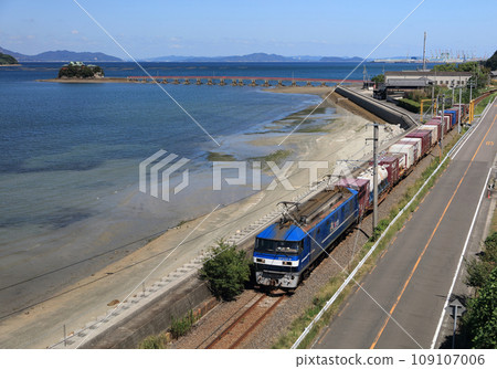 A freight train on the JR Yosan Line running through Setouchi and Tsushima Shrine, a guardian deity for children floating on the sea in Mino-cho, Mitoyo City, Kagawa Prefecture 109107006