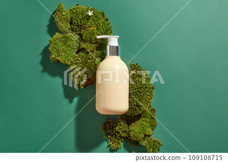 Top view of a yellow pump bottle container shampoo or cream placed on dark green background with green moss carpet. Natural organic cosmetic concept. Mockup, space for design Top view of a yellow pump bottle container shampoo or cream placed on dark green background with green moss carpet. Natural organic cosmetic concept. Mockup, space for design 109108715