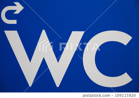 Close up photo of a white wc sign and an arrow indicating the turn to the toilet on a blue wall Close up photo of a white wc sign and an arrow indicating the turn to the toilet on a blue wall 109115920