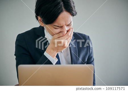 A male office worker wearing a mask covering his mouth with his hands A male office worker wearing a mask covering his mouth with his hands 109117571