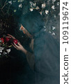 Stepmother witch gives poisoned red apple.Woman as witch in black offers red apple as symbol of temptation, poison. Fairy tale, white snow wizard concept. Spooky Halloween, cosplay. 109119674