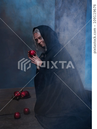 Stepmother witch gives poisoned red apple.Woman as witch in black offers red apple as symbol of temptation, poison. Fairy tale, white snow wizard concept. Spooky Halloween, cosplay. Stepmother witch gives poisoned red apple.Woman as witch in black offers red apple as symbol of temptation, poison. Fairy tale, white snow wizard concept. Spooky Halloween, cosplay. 109119676