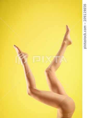 Woman wearing tights on yellow background, closeup of legs 109119856