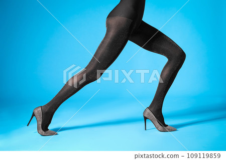 Woman wearing black tights and stylish shoes on blue background, closeup of legs Woman wearing black tights and stylish shoes on blue background, closeup of legs 109119859
