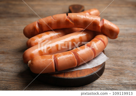 Delicious grilled sausages on wooden table, closeup 109119913