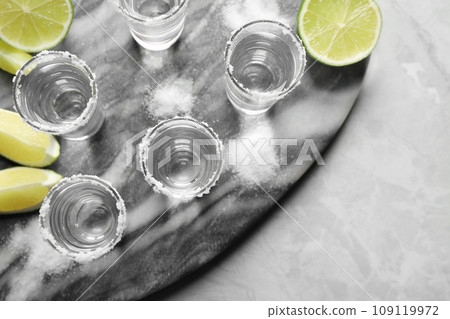 Mexican Tequila shots, lime slices and salt on grey marble table, top view 109119972