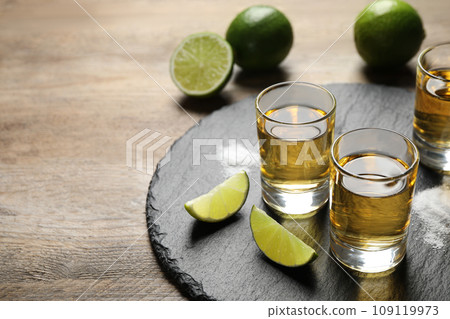 Mexican Tequila shots, lime slices and salt on wooden table Mexican Tequila shots, lime slices and salt on wooden table 109119973
