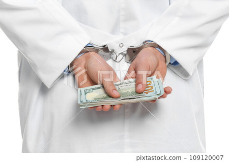 Doctor in handcuffs with bribe on white background, closeup. Corrupted medicine 109120007