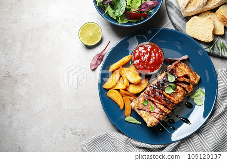 Delicious grilled ribs served on light grey table, flat lay. Space for text Delicious grilled ribs served on light grey table, flat lay. Space for text 109120137